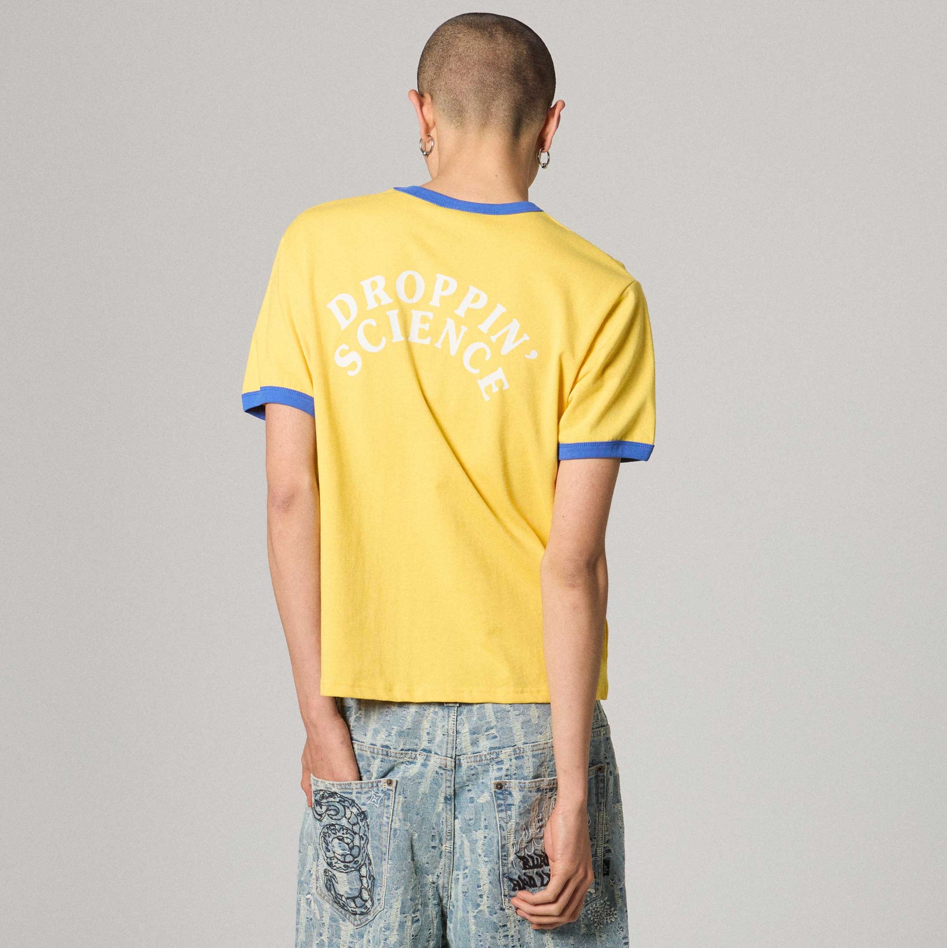 Camiseta ringer amarilla Droppin Science de la marca Grimey, con diseño gráfico en el frente y cuello contrastante.