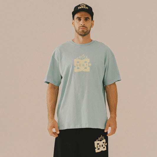 Camiseta azul de la colección The Swarm de DC Shoes y Grimey, con diseño gráfico visible en la imagen.