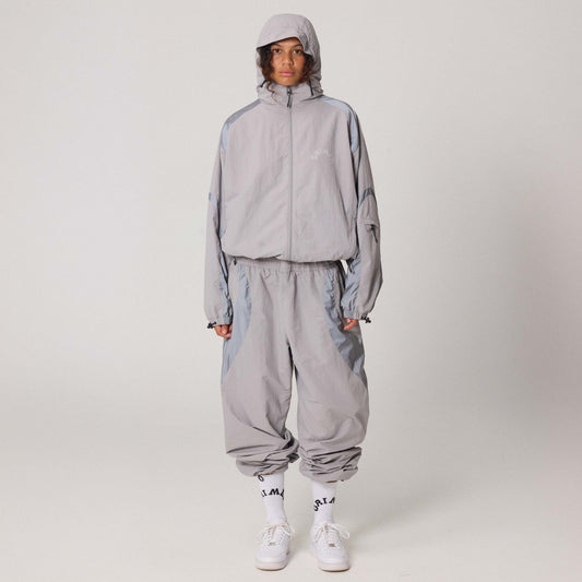Cortavientos gris The Infamous de la marca Grimey, con capucha y cierre frontal, diseñado para protección contra el viento.
